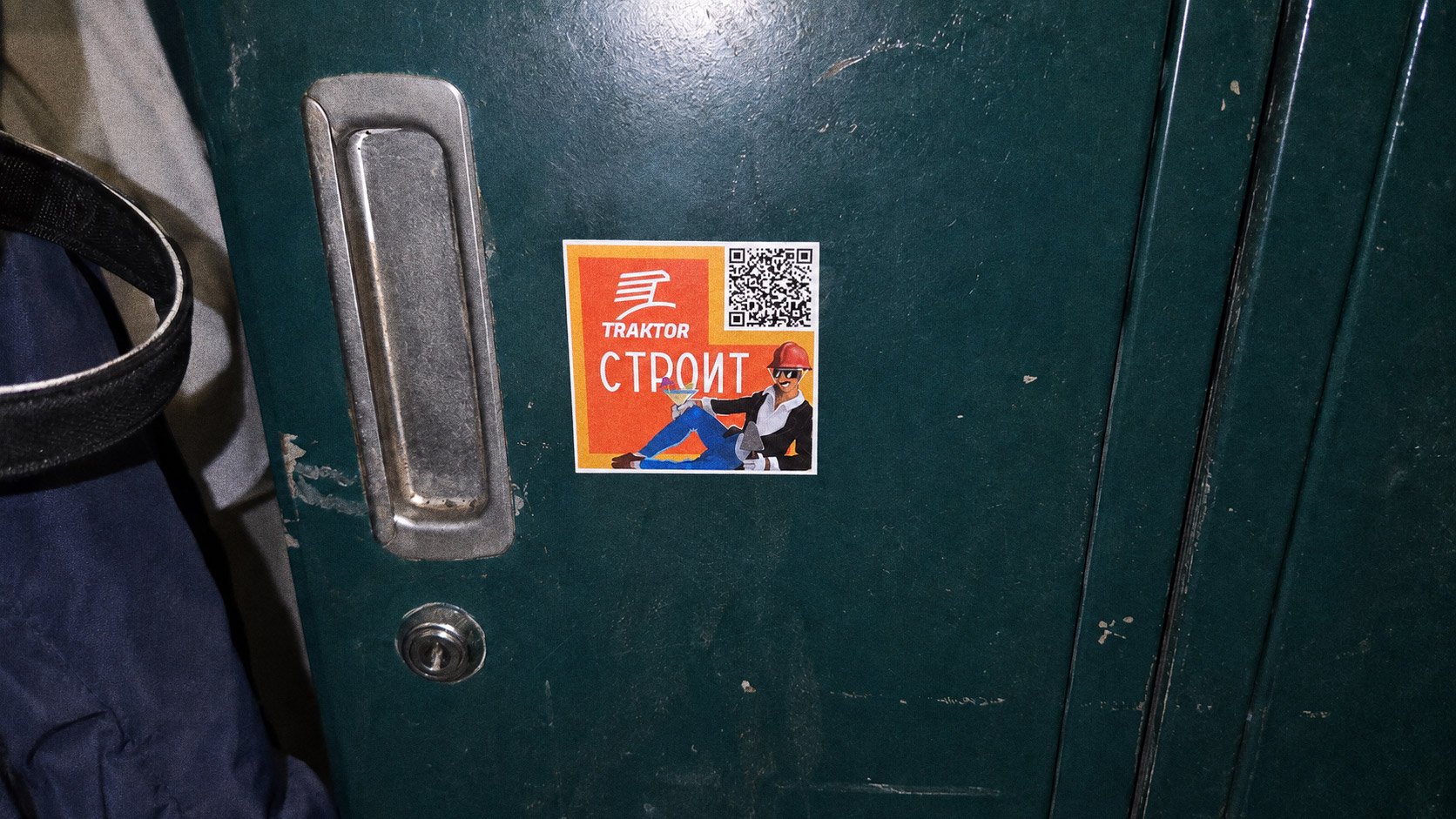 A Traktor 'Roet' digger sticker on a laptop lid, in a room full of people wearing lanyards