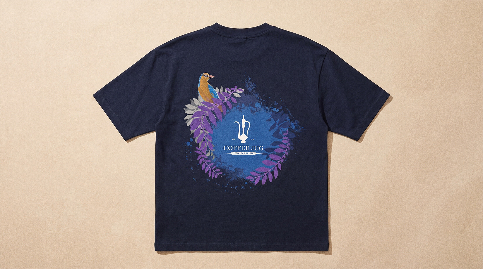 The tee laid flat, showing the full back print — bird, foliage wreath and logo
