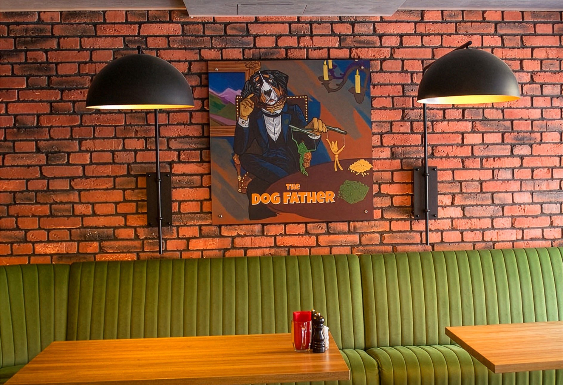 The Dog Father framed and mounted above a booth, between two wall lamps