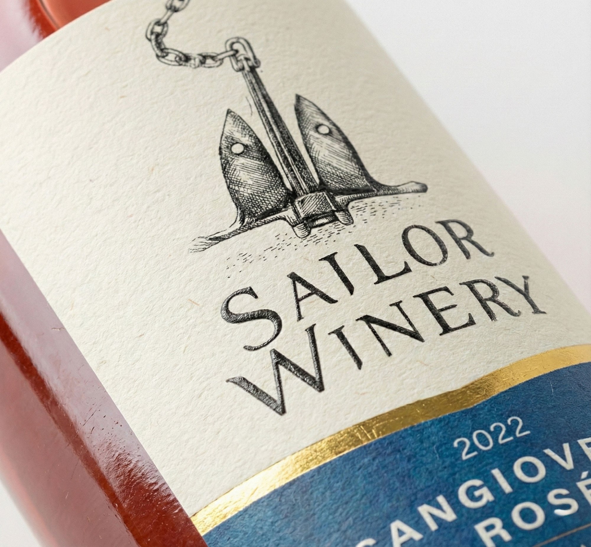 The Ros&eacute; label in close-up: the engraved anchor and its hanging chain filling the upper half