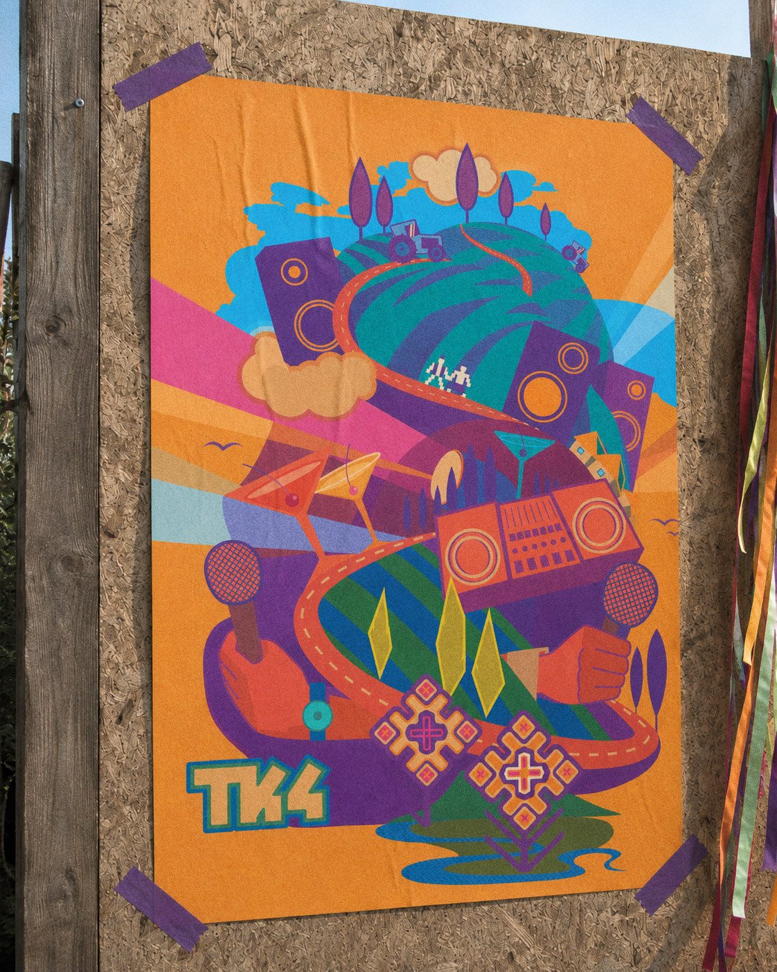 The Tractor Camp 4 poster taped to a board with purple tape — a hill of speakers and tractors growing out of two hands holding a boombox, ribbons at the edge