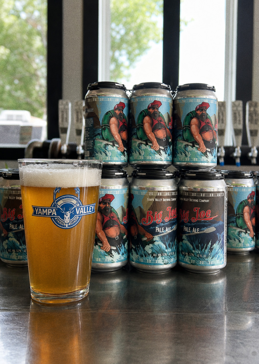 Big Joe Pale Ale — cans stacked behind a poured glass in the taproom